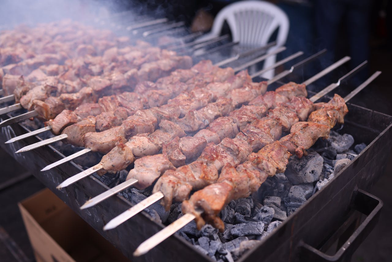 Charcoal grill sizzling with appetizing roasted meat skewers, emitting mouth-watering aroma.
